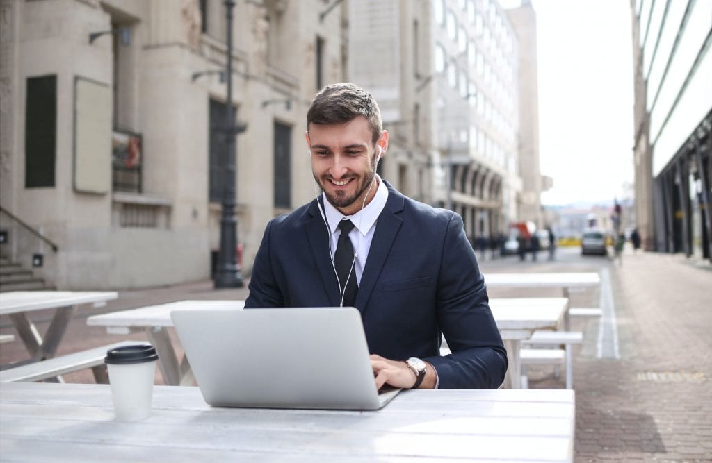 man sitting in front of a laptop smiling be successful with OTRS