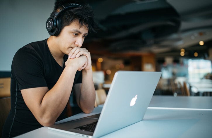 man with headphones in front of a laptop