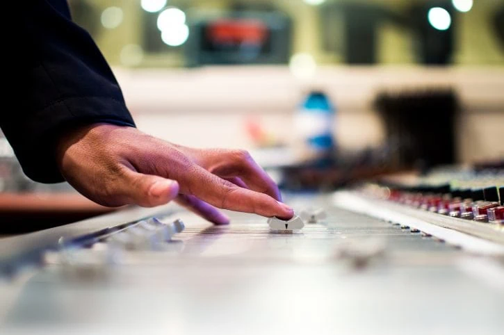 Hand sliding a controller on a mixing console